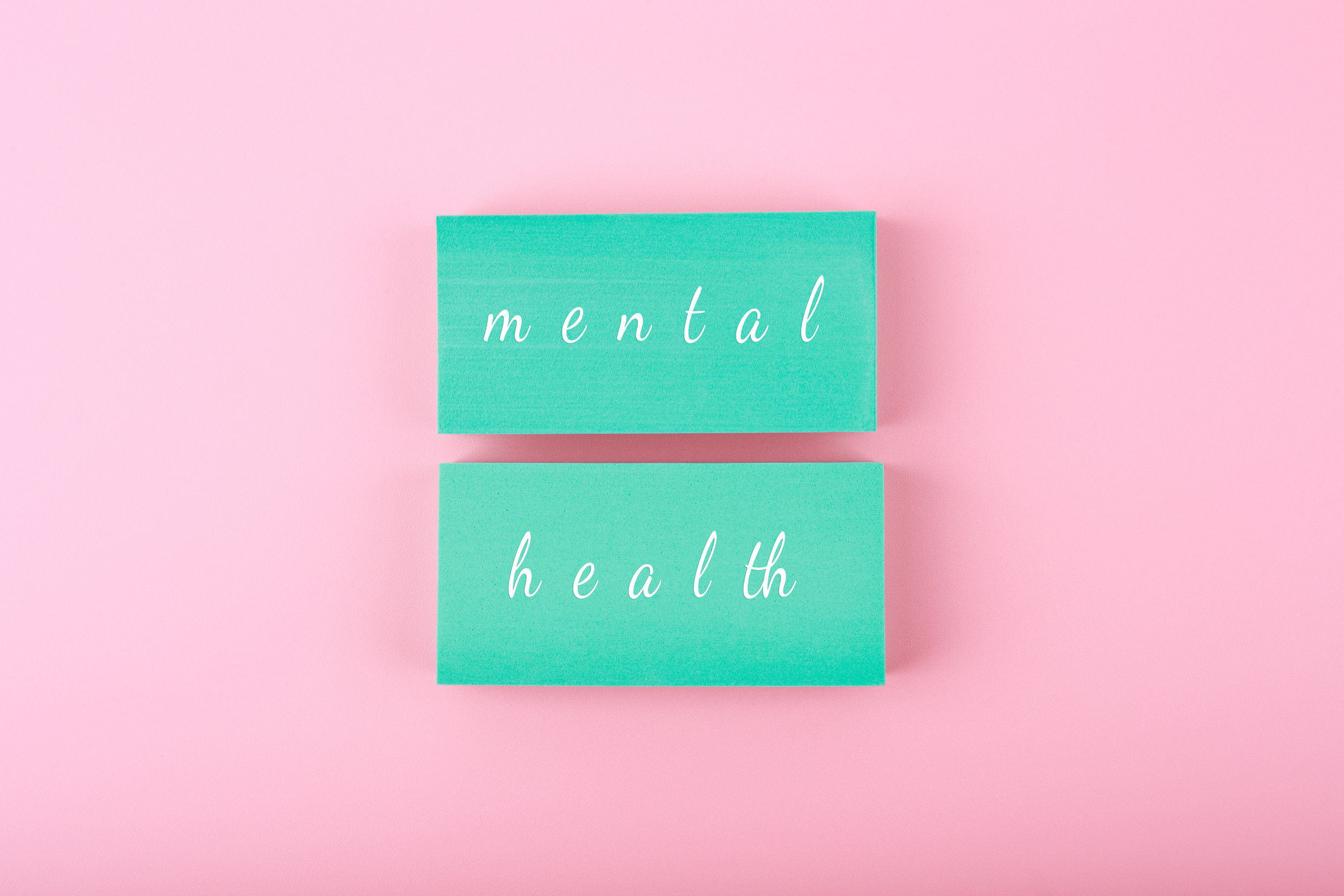 Two green cards with the words “mental” and “health” in white script are placed on a pink background, symbolizing the importance of Mental Health Care in Baxter MN.