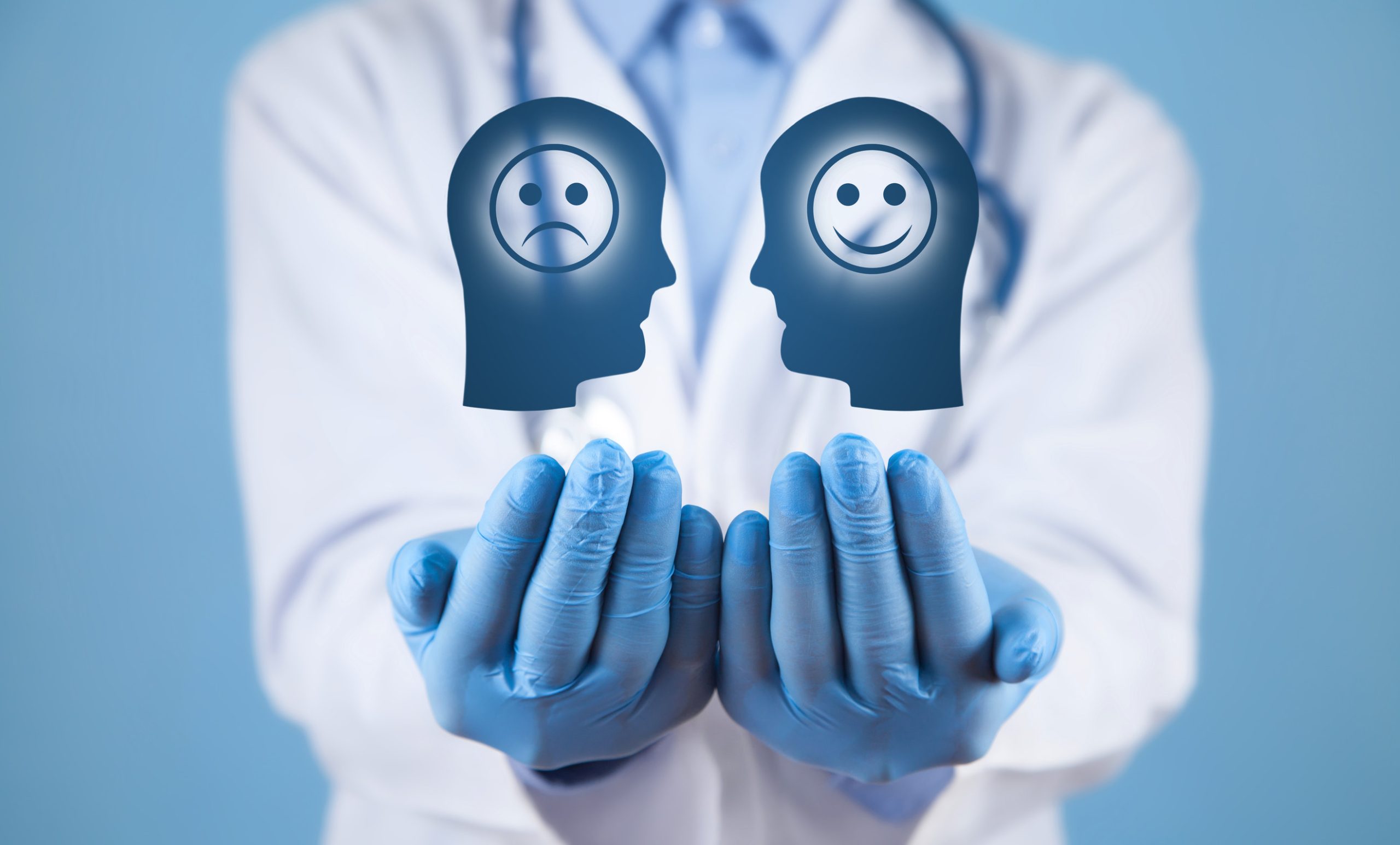 A doctor in a white coat and blue gloves holds out icons of a sad face and a happy face, symbolizing mental health and emotional well-being—highlighting Psychiatry Services available in Baxter Minnesota.