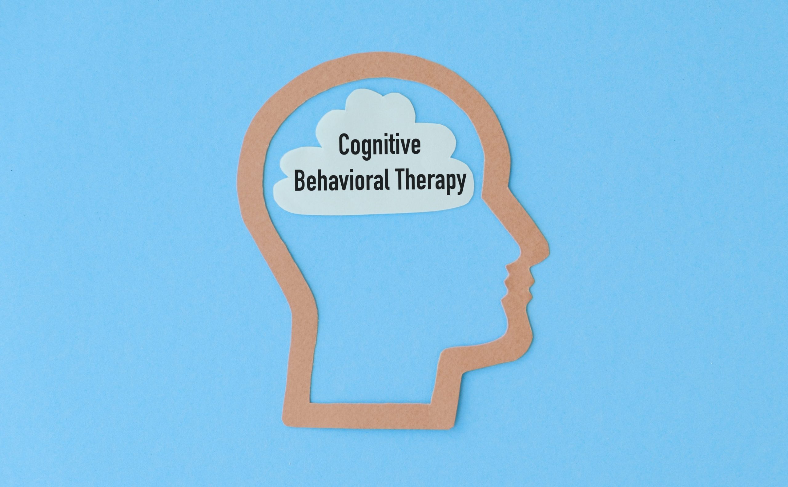 A paper cutout of a human head on a blue background with a cloud inside the head containing the words